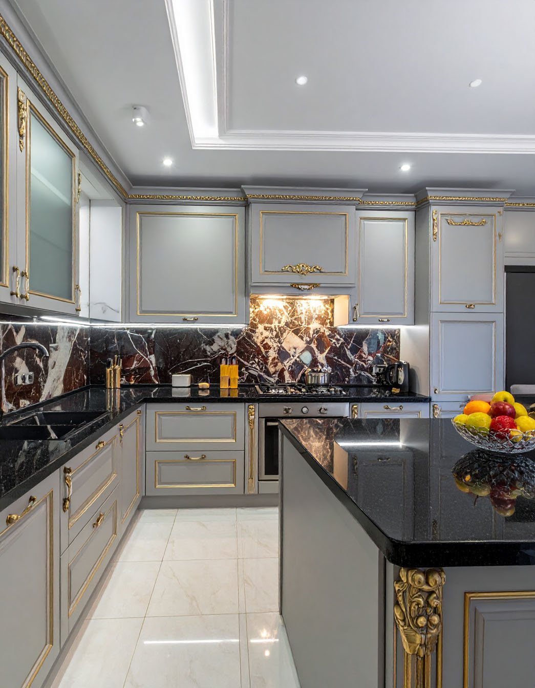 Cuisine luxueuse gris et or avec îlot et plans de travail en granit noir, crédence en marbre