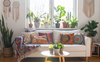 Salon bohème lumineux avec canapé blanc, coussins colorés, plantes et attrape-rêves