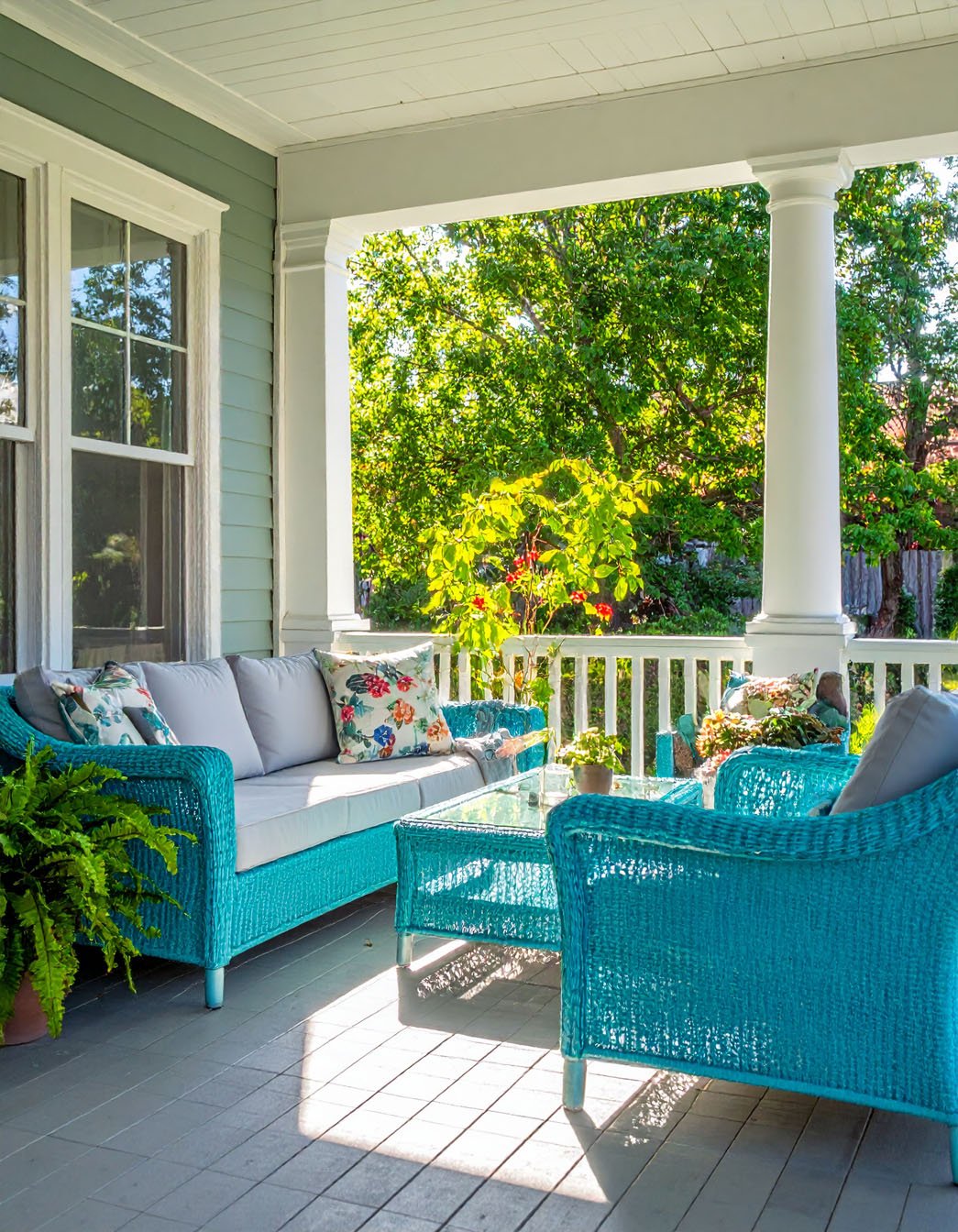 Porche avec salon de jardin en rotin bleu turquoise vif et coussins fleuris