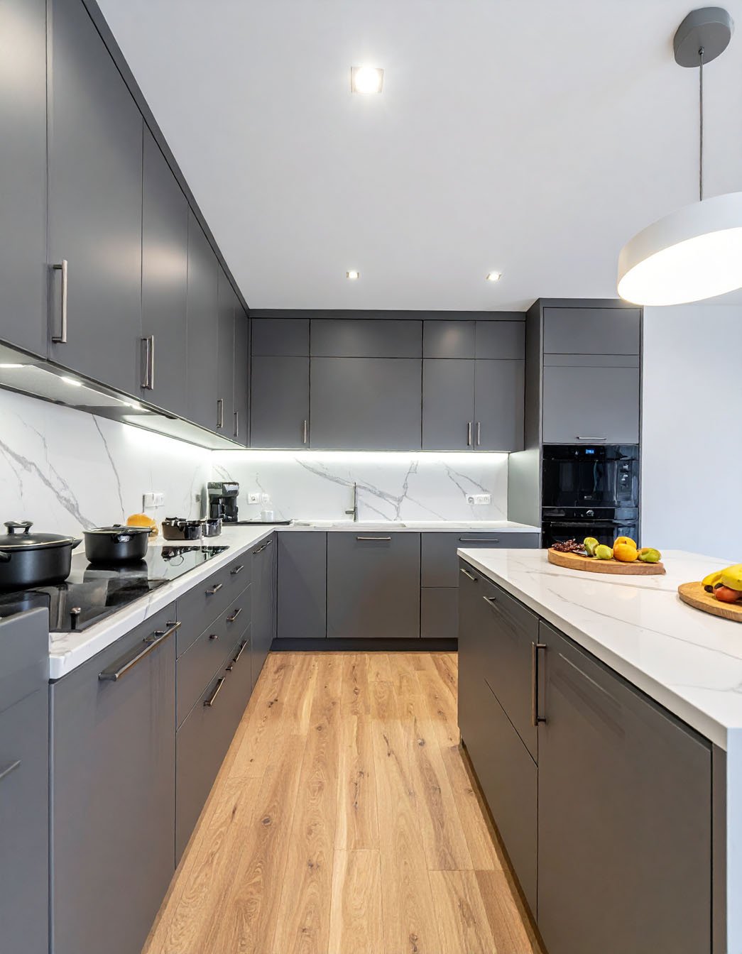 Cuisine en U avec meubles gris mat, plan de travail blanc et parquet clair