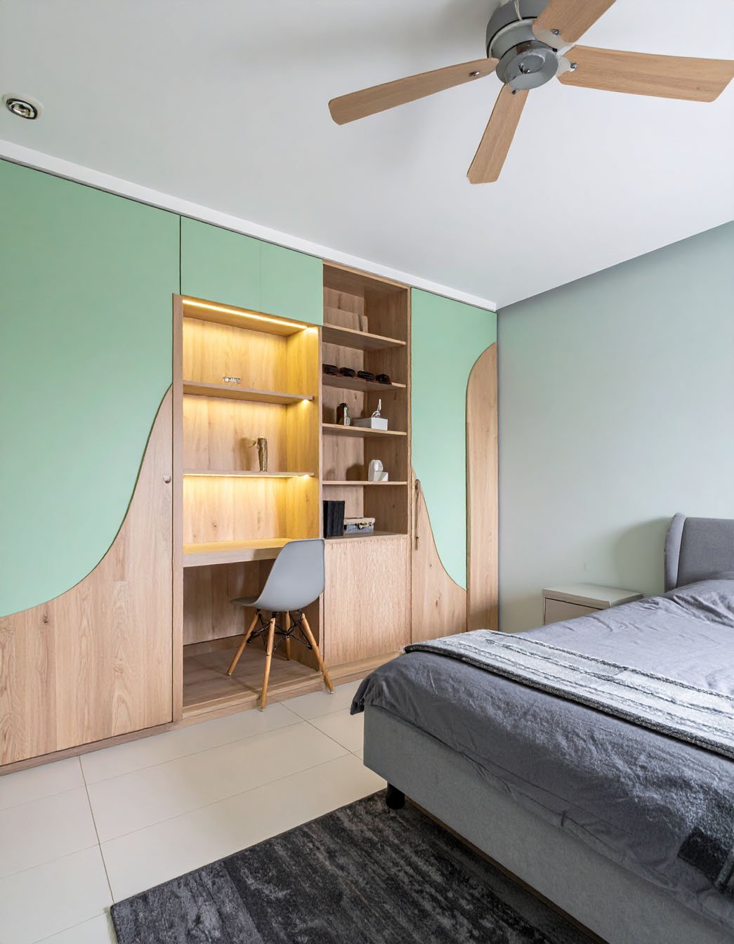 Chambre avec lit gris, grand meuble mural en bois clair et vert menthe avec bureau intégré