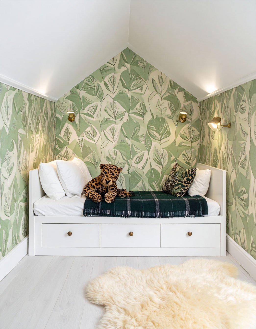 Chambre d'enfant mansardée avec lit banquette blanc, papier peint à motifs de feuilles vertes