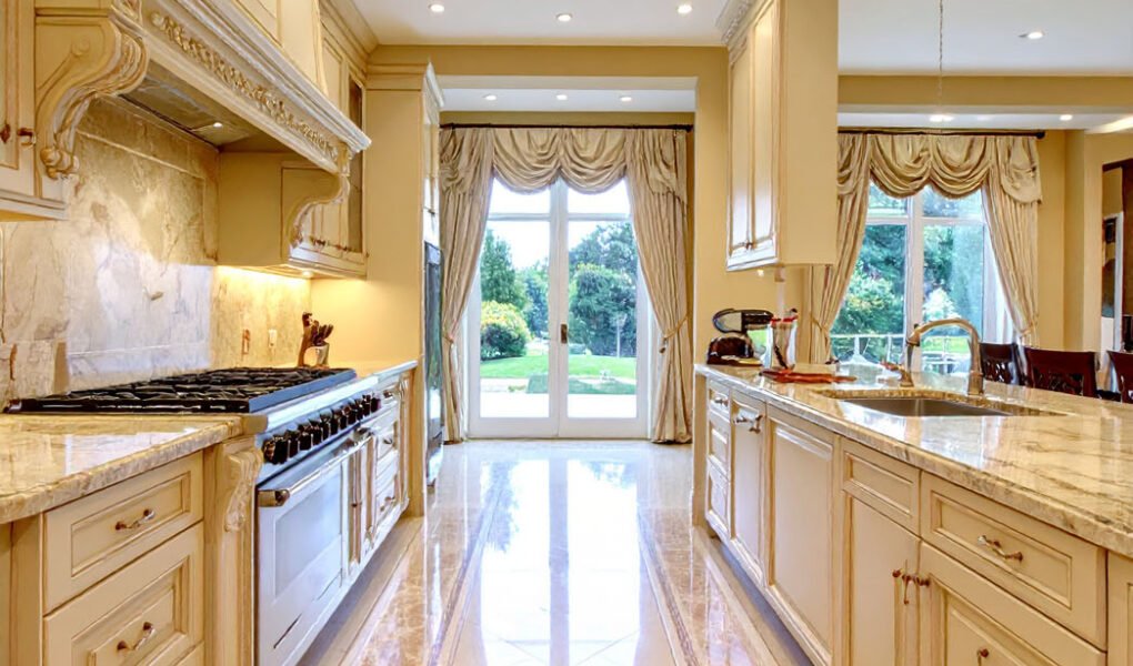 Cuisine de luxe couleur crème avec sol en marbre à motifs et vue sur jardin