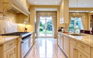 Cuisine de luxe couleur crème avec sol en marbre à motifs et vue sur jardin