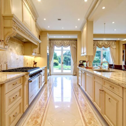 Cuisine de luxe couleur crème avec sol en marbre à motifs et vue sur jardin