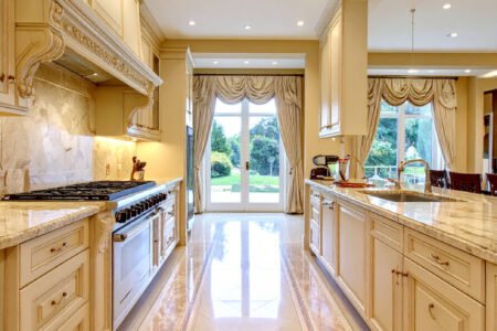 Cuisine de luxe couleur crème avec sol en marbre à motifs et vue sur jardin