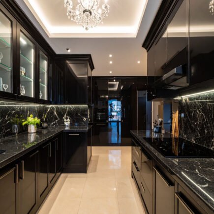 Cuisine luxueuse noire avec plans de travail en marbre noir et lustre en cristal