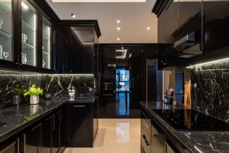 Cuisine luxueuse noire avec plans de travail en marbre noir et lustre en cristal