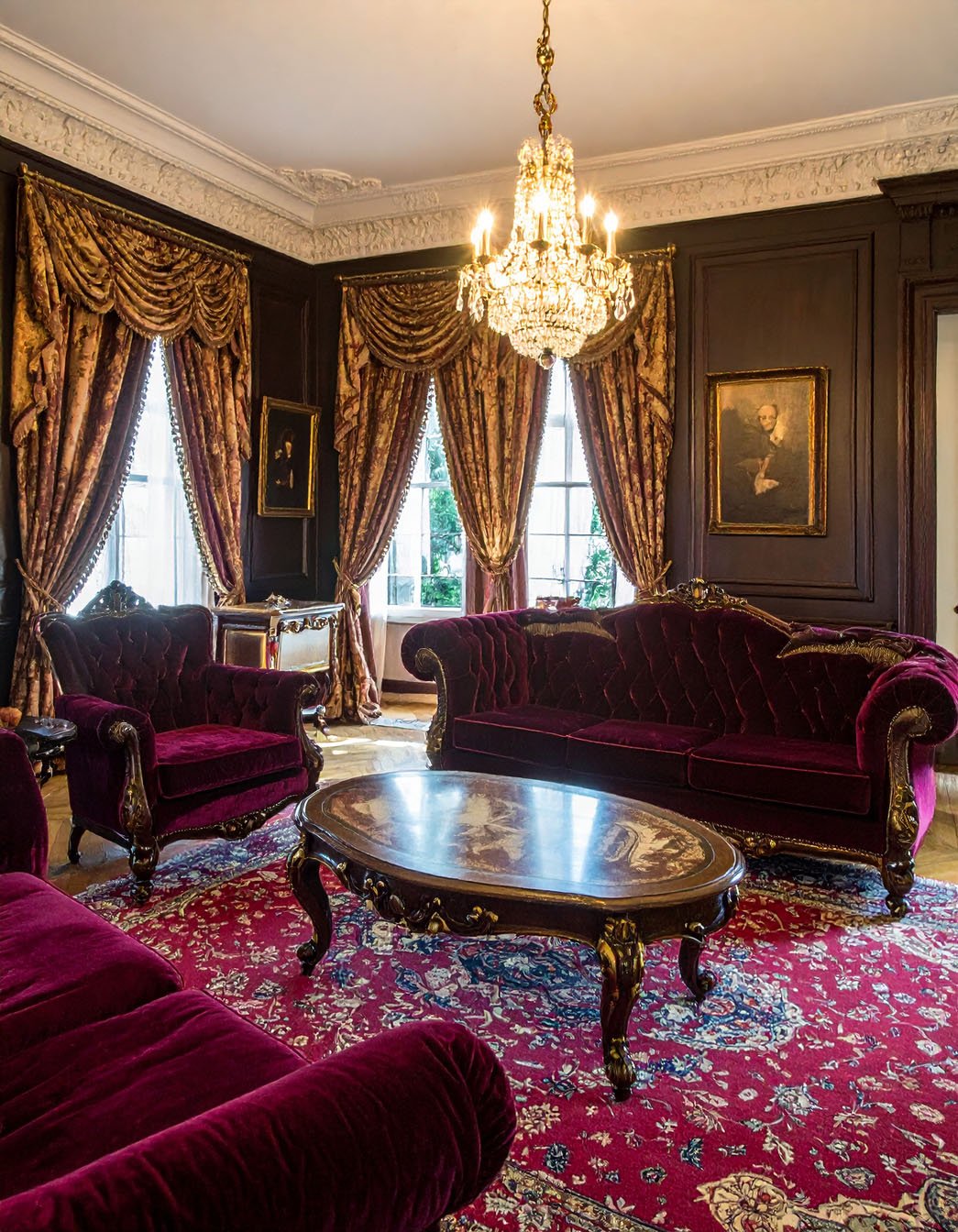 Salon opulent avec canapés en velours bordeaux, tapis persan rouge et lustre en cristal