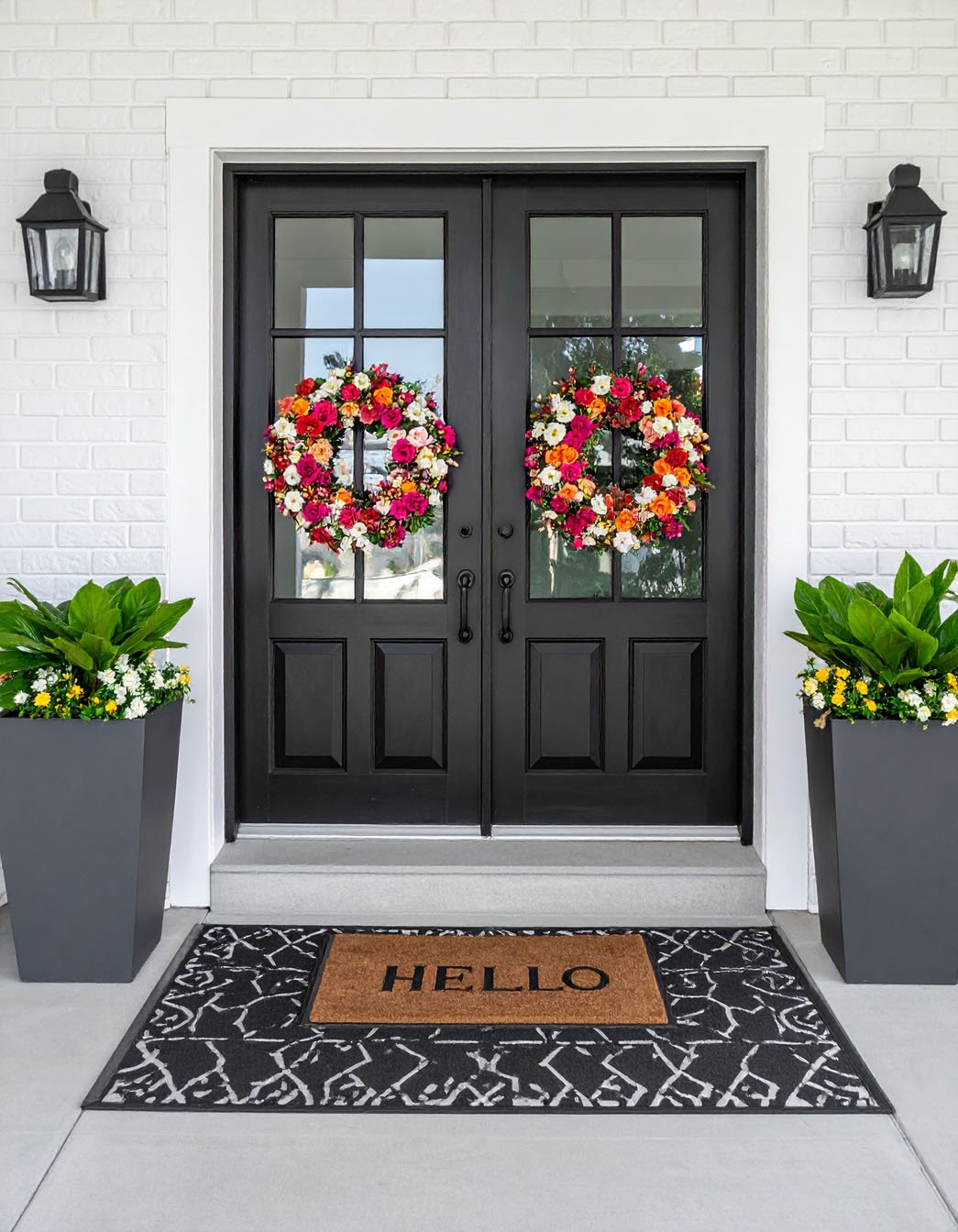 Double porte d'entrée noire vitrée avec couronnes florales colorées