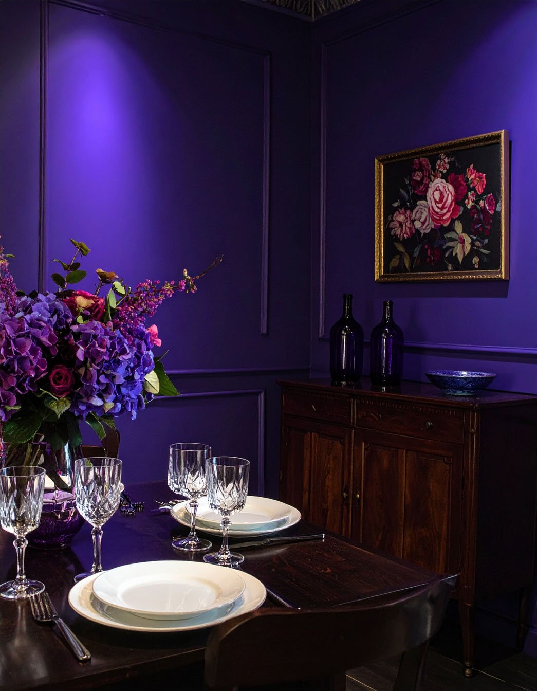 Salon avec murs et canapé violets, et grand tableau abstrait coloré
