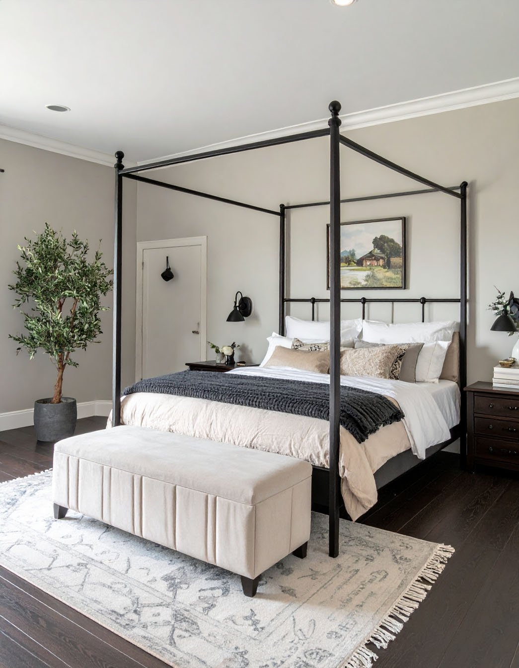 Chambre avec lit à baldaquin en métal noir, banc beige et olivier en pot