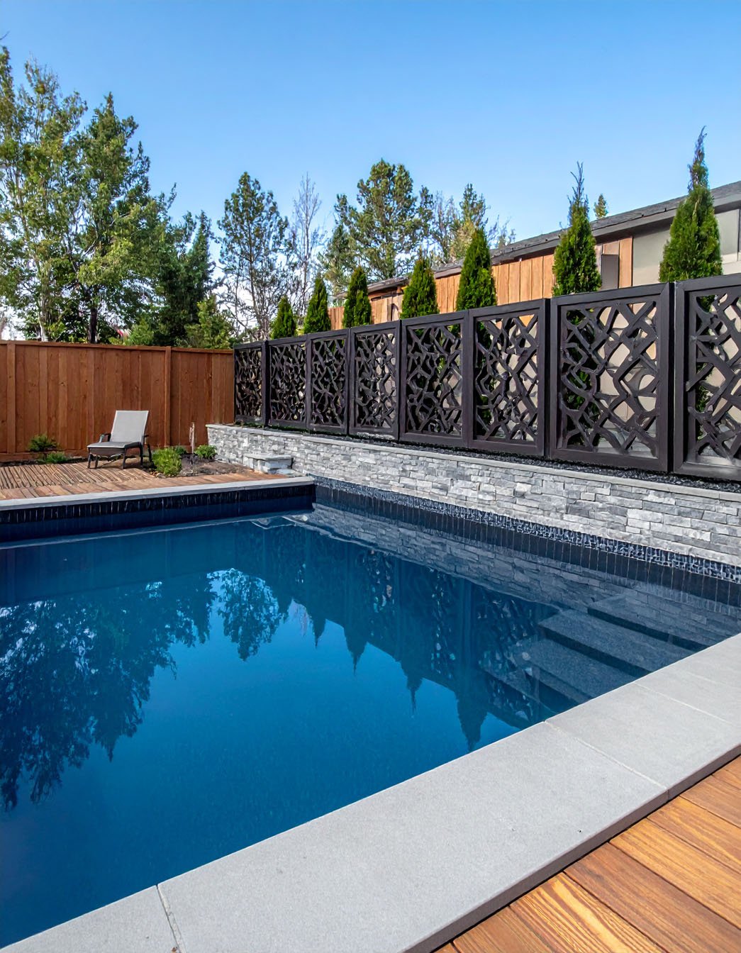 Piscine entourée d'une clôture en bois décorative et de chaises longues