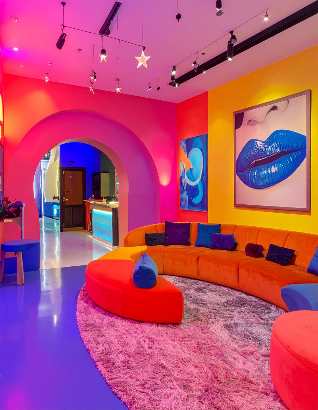 Espace de fête coloré avec canapé courbe orange, murs aux couleurs vives et tableau pop art