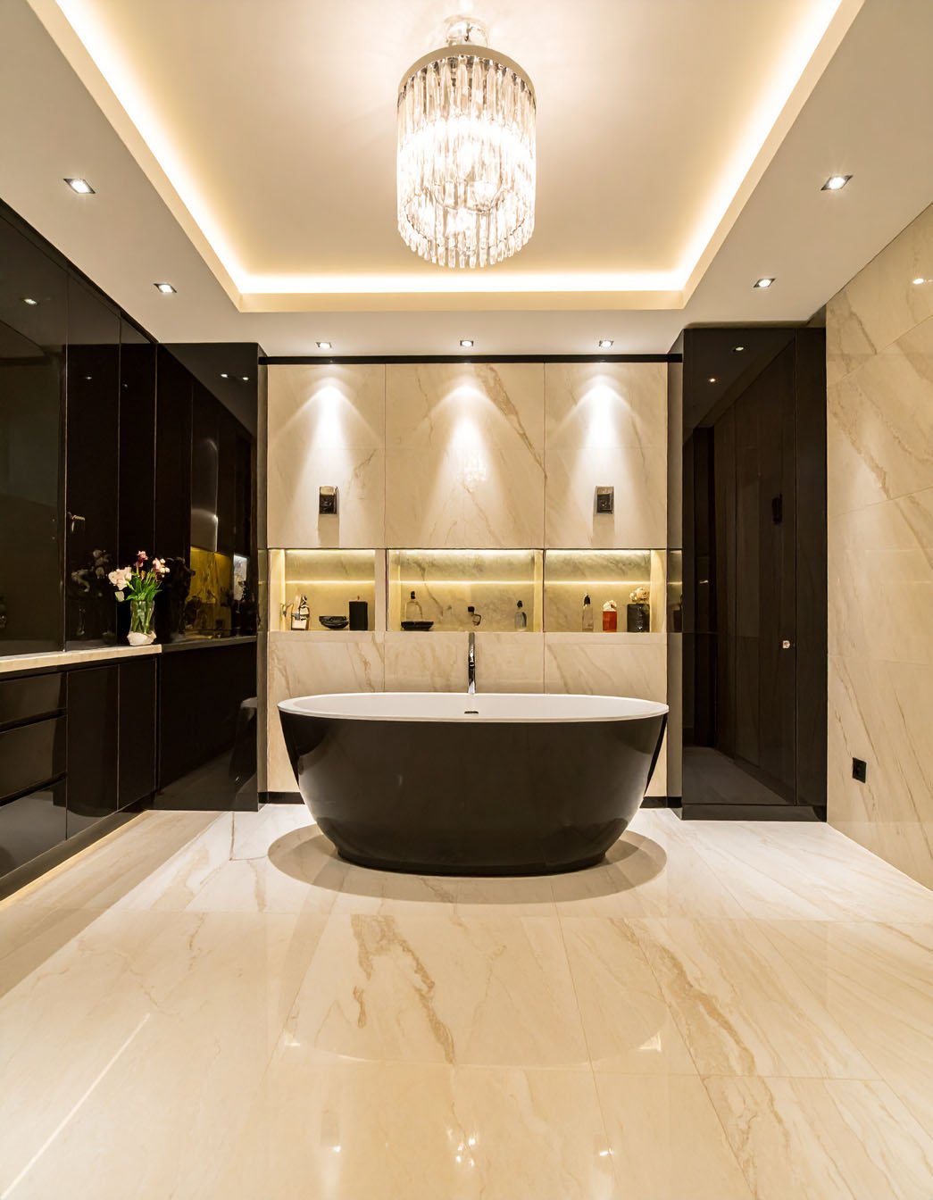 Salle de bain luxueuse avec baignoire îlot noire, murs en marbre et lustre en cristal