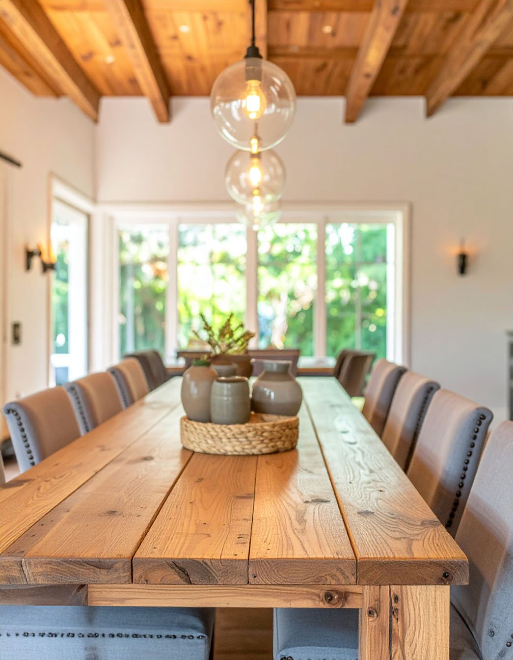 Grande table de salle à manger en bois avec chaises grises et suspensions globes en verre