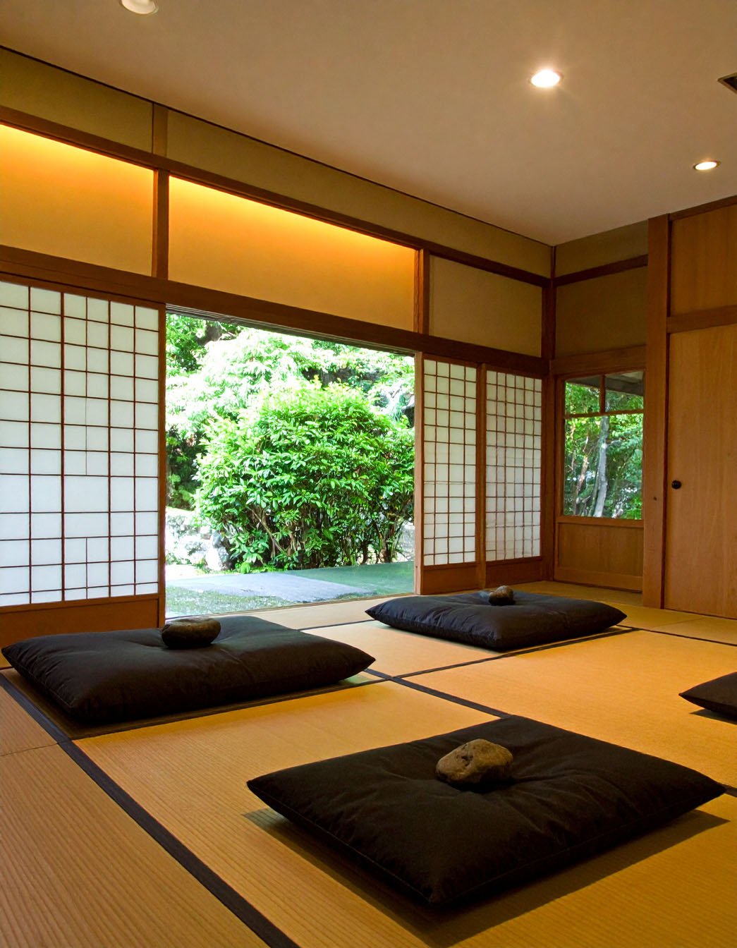 Pièce de style japonais avec tatamis, coussins noirs et portes coulissantes shoji