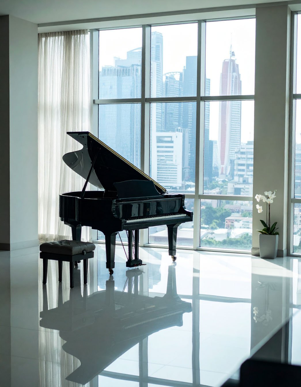 Piano à queue noir dans une pièce lumineuse avec grandes baies vitrées et vue sur la ville