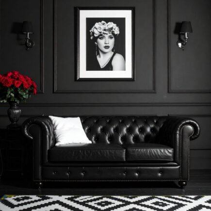 Salon avec murs gris, canapé Chesterfield en cuir noir et tapis à motifs graphiques