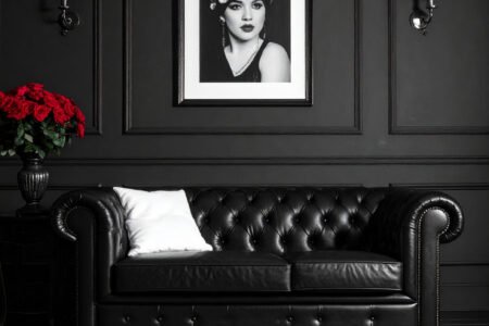 Salon avec murs gris, canapé Chesterfield en cuir noir et tapis à motifs graphiques