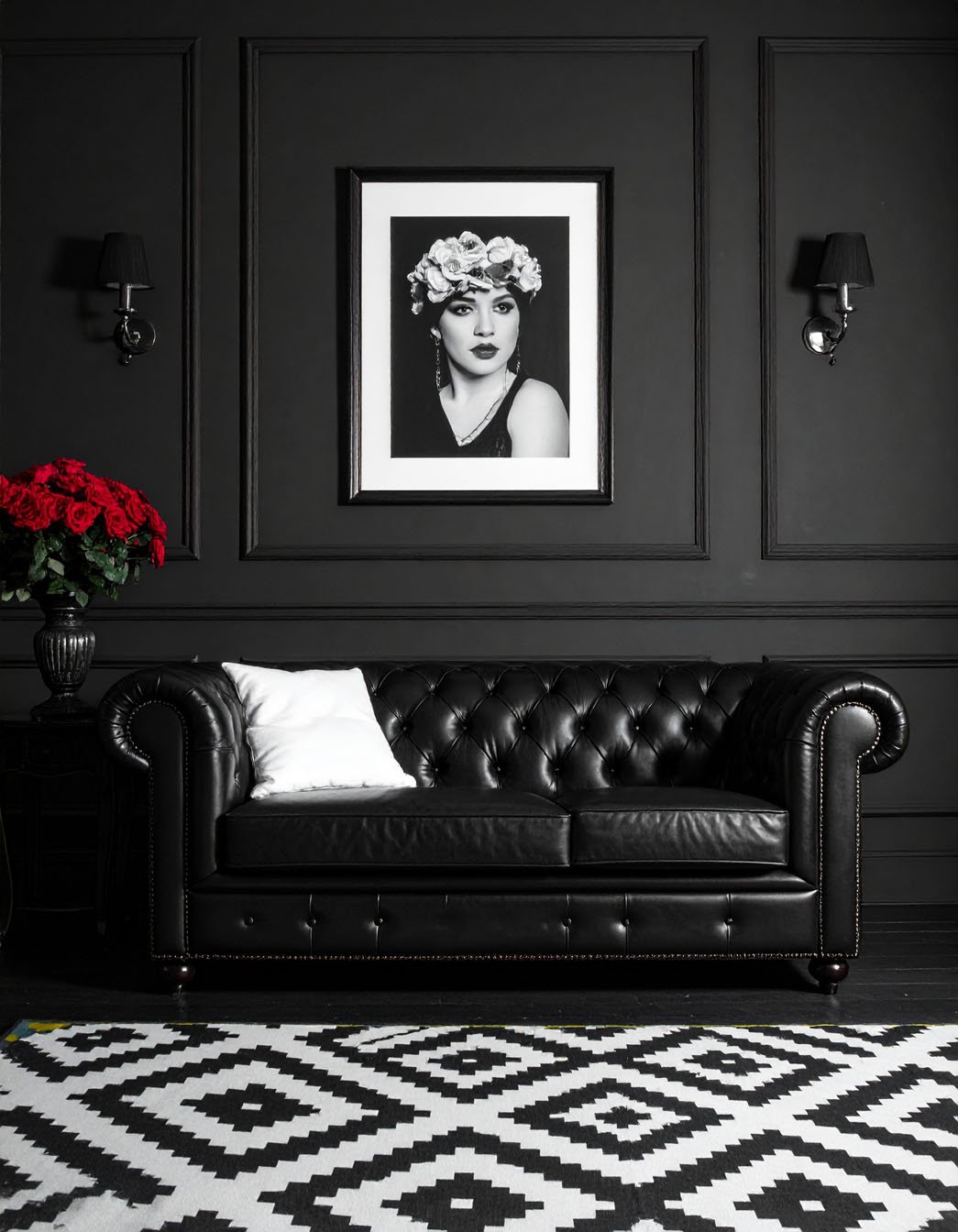 Salon avec murs gris, canapé Chesterfield en cuir noir et tapis à motifs graphiques