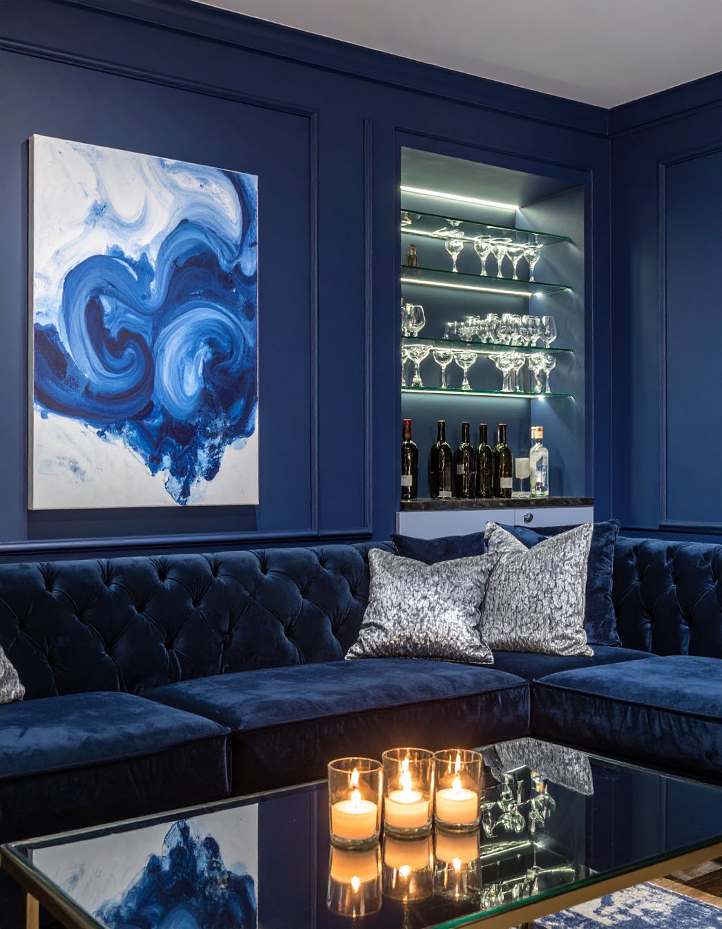 Salon avec murs bleu marine, canapé en velours bleu, et bouquet de fleurs blanches