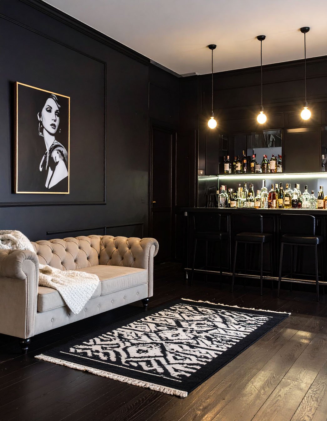 Bar sombre et élégant avec canapé Chesterfield beige et tapis à motifs graphiques