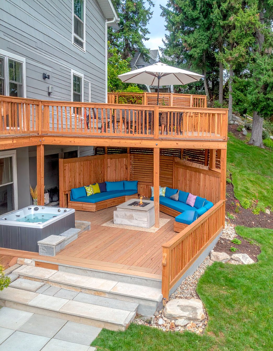 Terrasse en bois avec jacuzzi encastré et chaises longues, entourée d'arbres