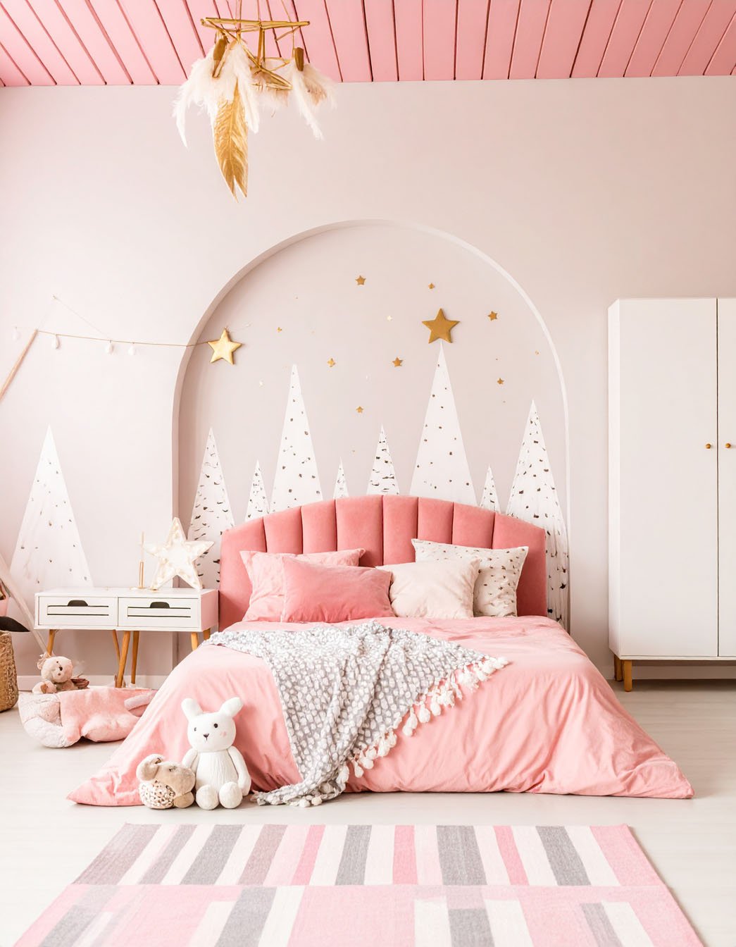 Chambre d'enfant rose avec lit à tête de lit festonnée, décorations murales de montagnes et étoiles