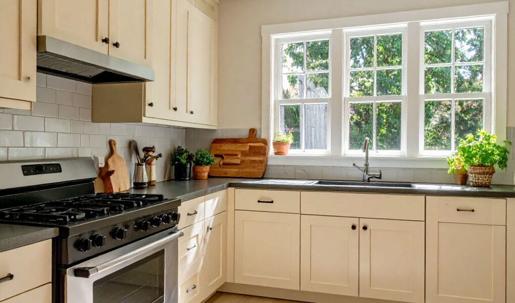 Cuisine avec meubles couleur crème, plan de travail foncé et tapis à motifs
