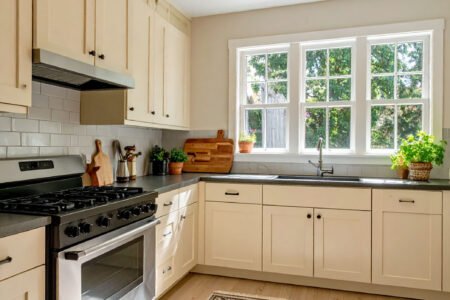 Cuisine avec meubles couleur crème, plan de travail foncé et tapis à motifs