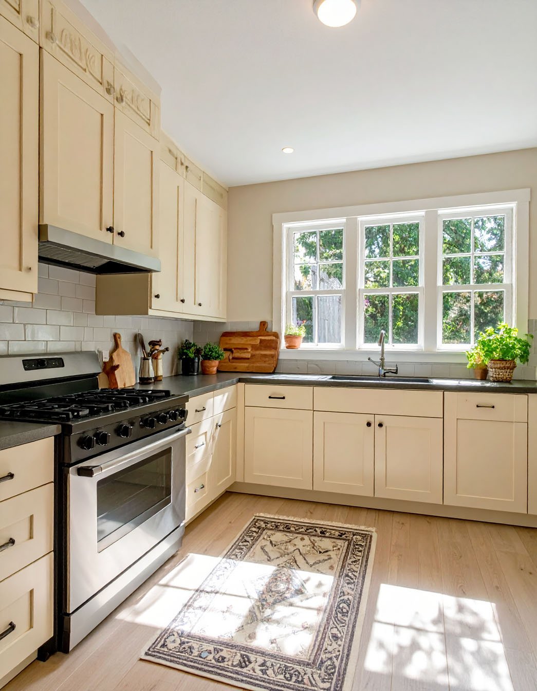 Cuisine avec meubles couleur crème, plan de travail foncé et tapis à motifs