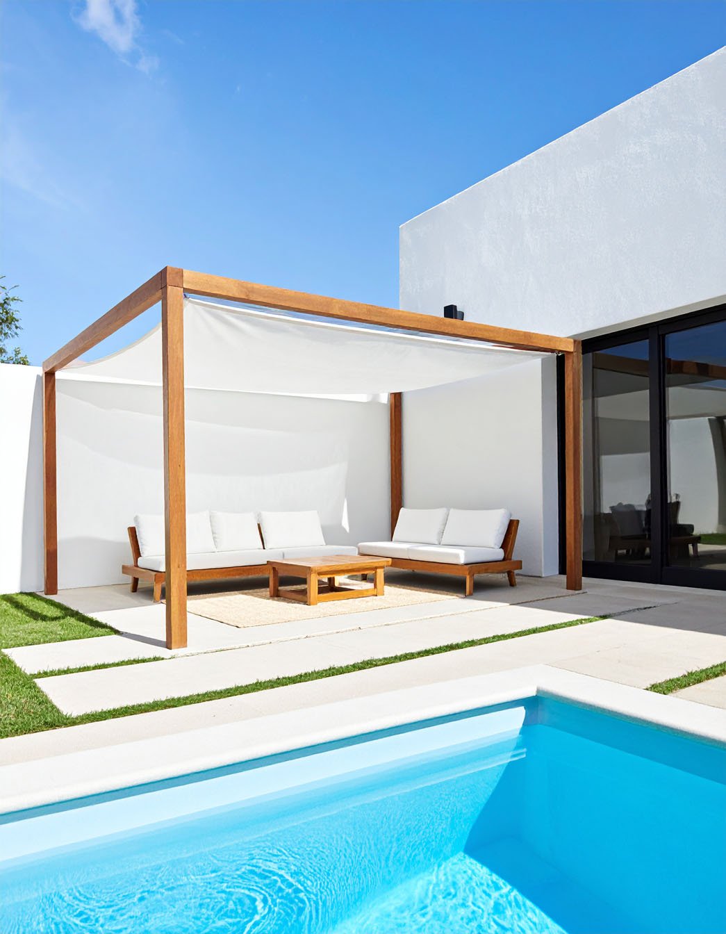 Piscine avec terrasse en bois et pergola, chaises longues et vue sur la campagne
