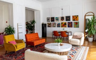 Salon éclectique avec murs blancs, parquet à chevrons, canapés et fauteuils colorés, tapis orientaux