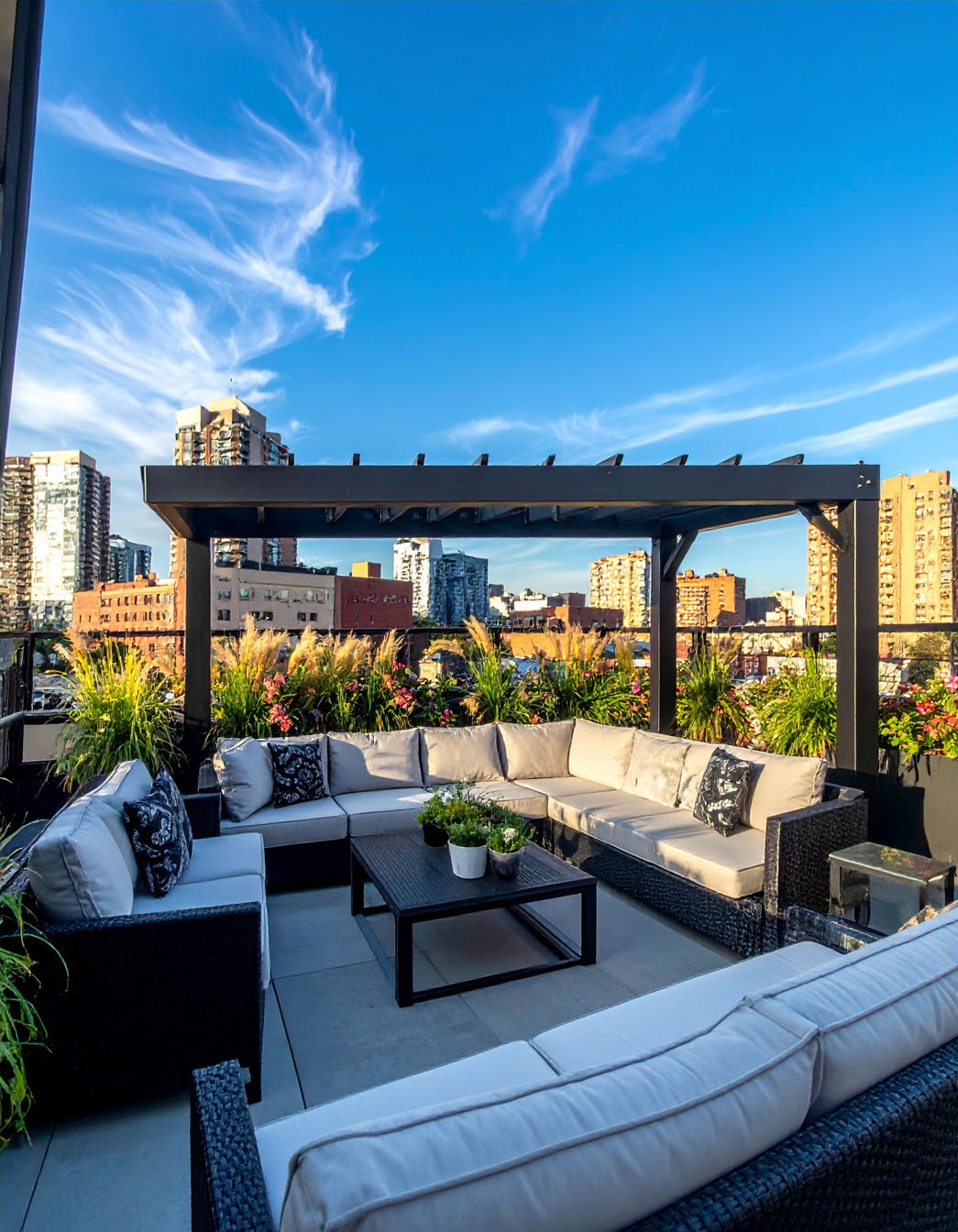 Toit-terrasse aménagé avec grand canapé d'angle en résine tressée et vue sur la ville