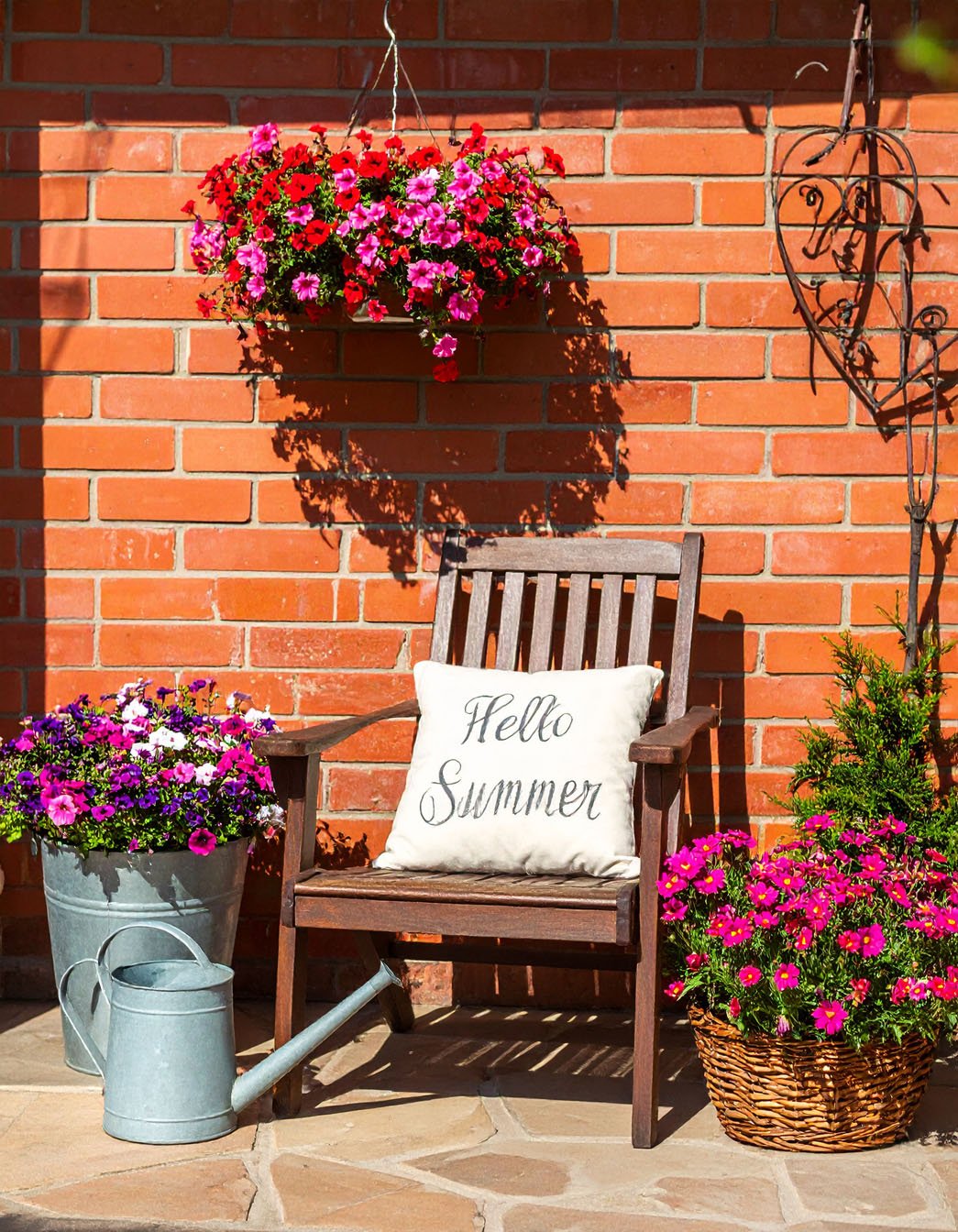 Coin été avec chaise en bois, coussin 'Hello Summer', fleurs et mur en briques