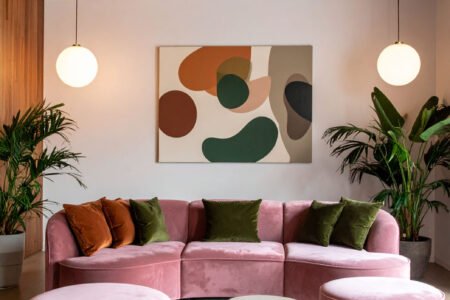 Salon moderne avec canapé modulable rose poudré, poufs assortis et tableau abstrait