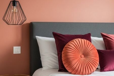 Lit gris avec coussins en velours devant un mur terracotta