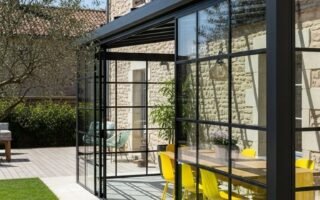 Véranda de style atelier avec structure noire et chaises jaunes
