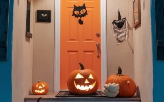 Porche avec une porte orange decoree de citrouilles et de chauves souris en papier