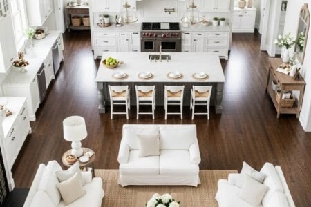 Vaste espace de vie blanc avec cuisine symétrique et parquet foncé