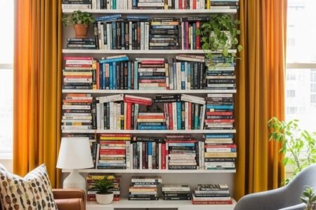 Bibliothèque murale massive entourant une fenêtre avec des rideaux jaunes