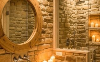 Salle de bains spa avec murs en pierre meuble en bois et miroir rond en bois