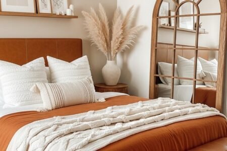 Chambre adulte beige avec linge de lit terracotta rouille et miroir arche